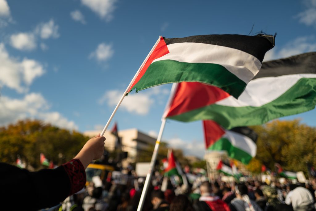 Protesters waving Palestinian flags during a demonstration, reflecting U.S. policy shifts and regional tensions in the Middle East.