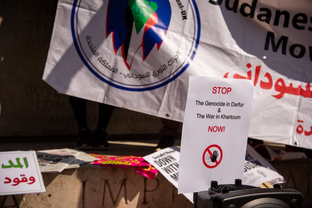 Protest signs and banners highlight global demands to stop atrocities in Darfur and Khartoum as civilians call for protection and accountability.