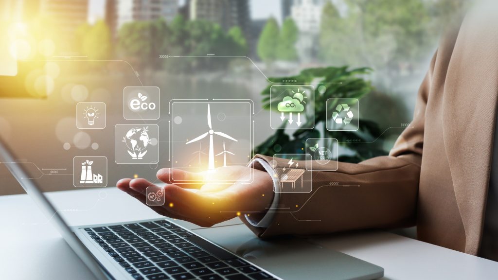 A person working at a laptop with digital icons representing renewable energy, sustainability, and eco-technologies hovering above their hand.
