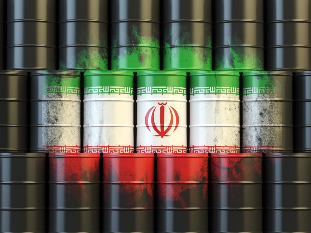 Oil barrels painted with the Iranian flag stacked against black barrels, symbolising Iran oil exports, sanctions pressure, and global energy market constraints