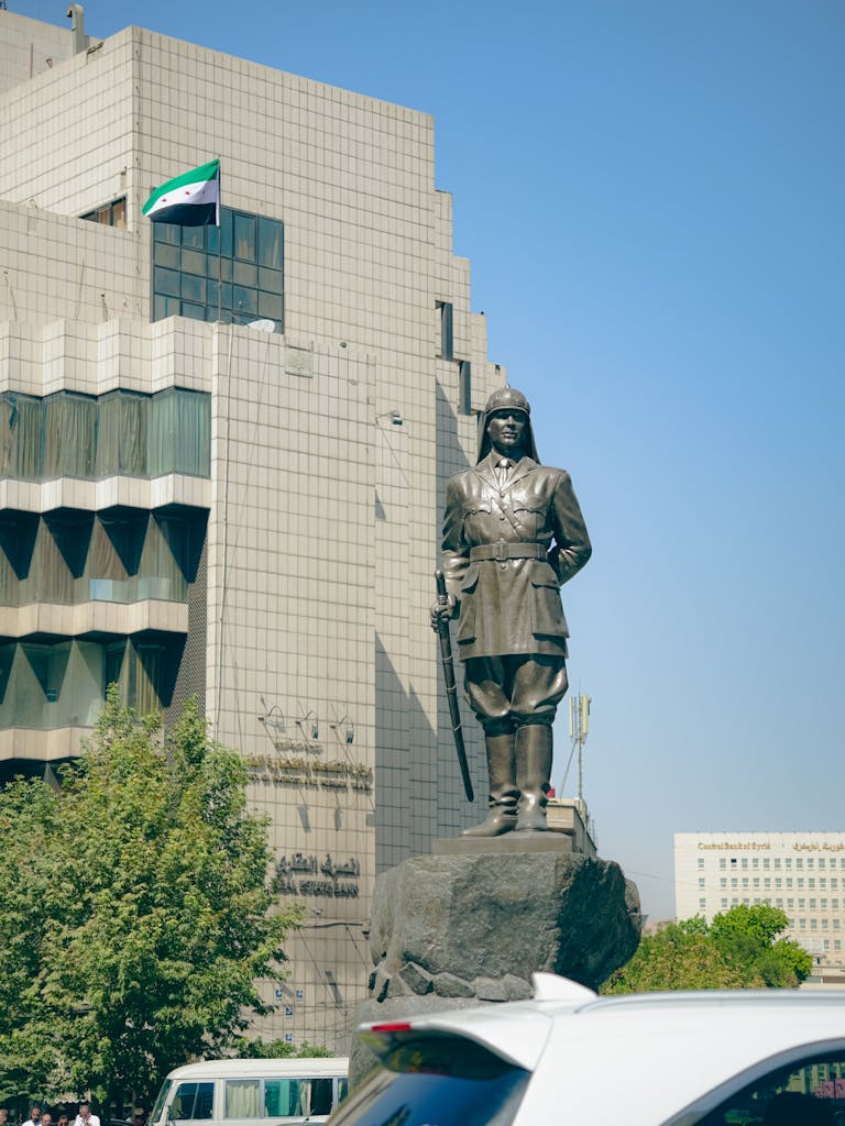 Statue in Damascus with modern architecture and Syrian flag