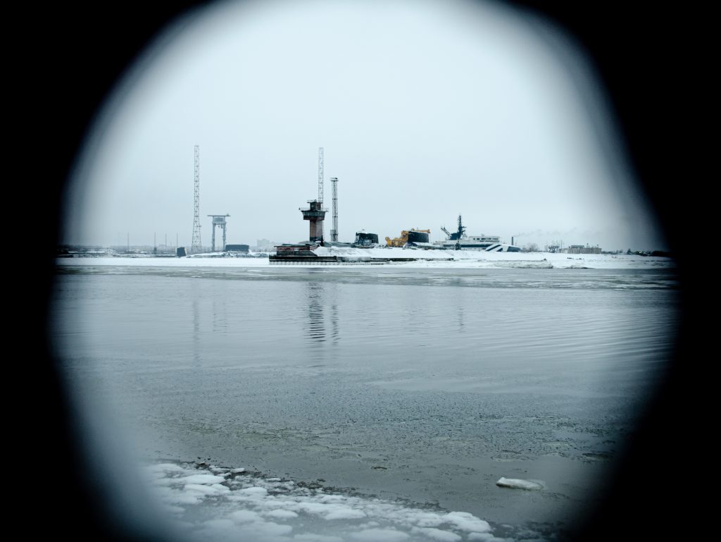 Arctic industrial infrastructure viewed through scope highlighting surveillance, strategic monitoring, and environmental change in polar regions