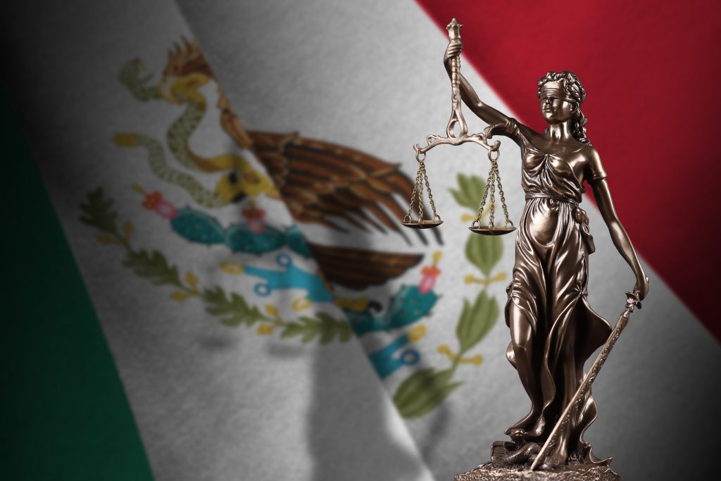 Statue of Lady Justice with scales in front of Mexican flag representing justice, accountability, and legal institutions