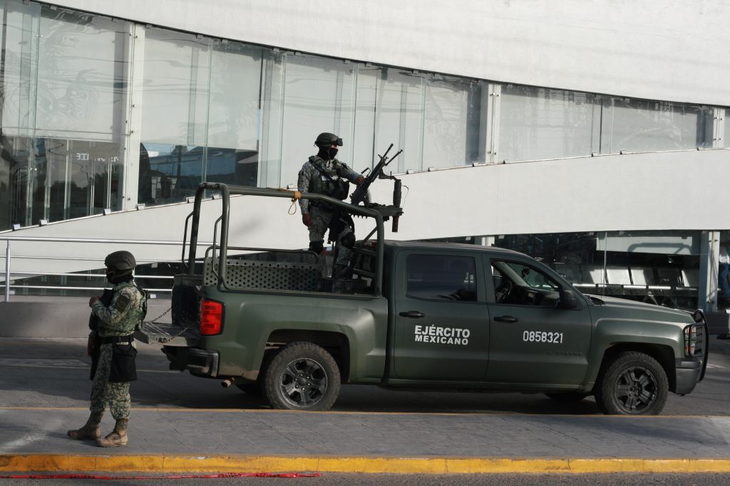 Mexican army soldiers on patrol in armed vehicle in urban area, illustrating militarised security response to organised crime