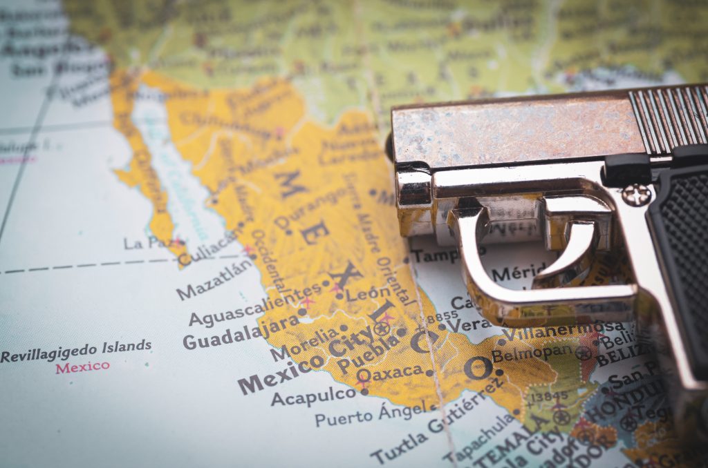 Handgun placed over map of Mexico symbolising geographic spread of violence and organised crime networks
