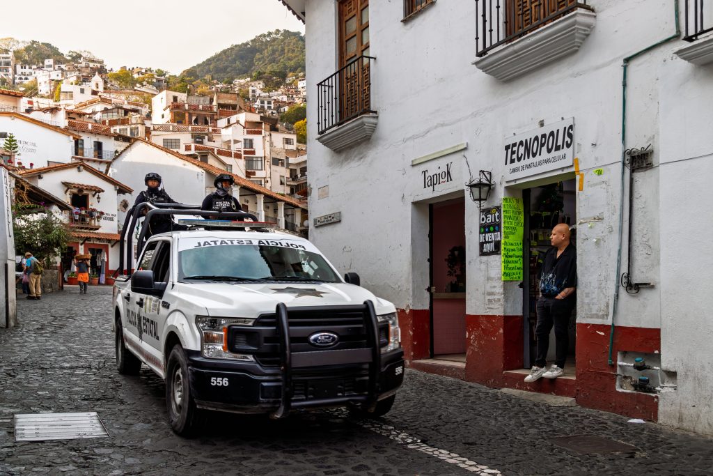 Mexican police patrol vehicle driving through town street, reflecting local security presence and policing challenges