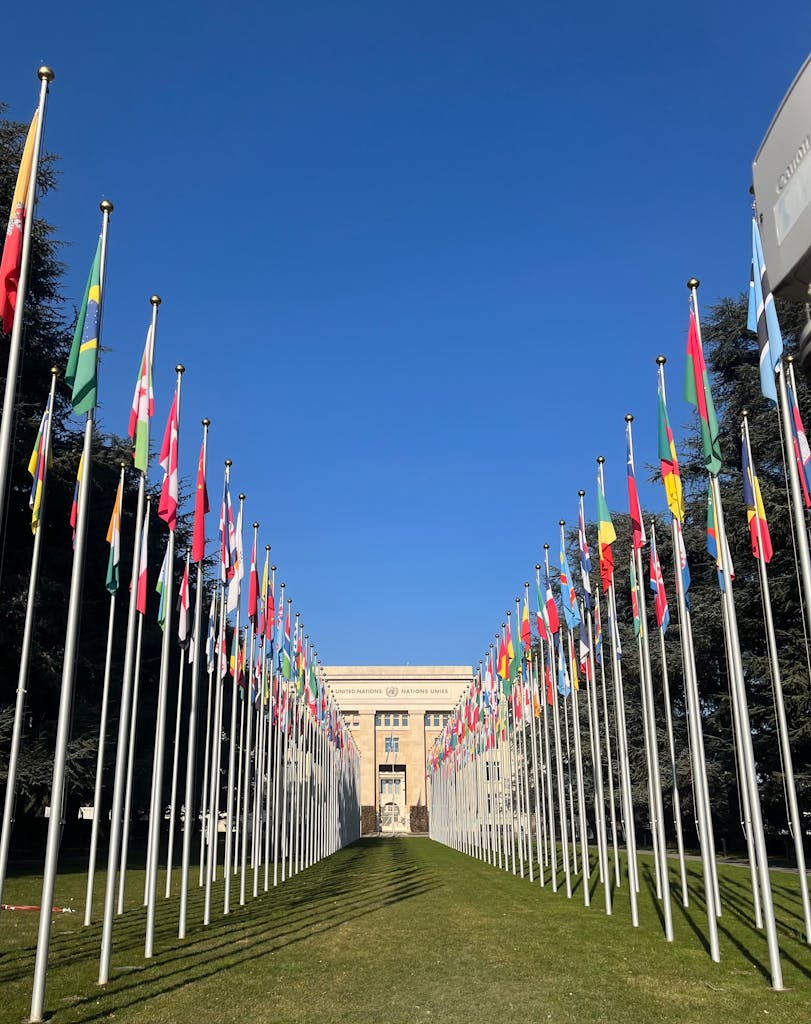 Flags outside the United Nations Office in Geneva under a clear blue sky.